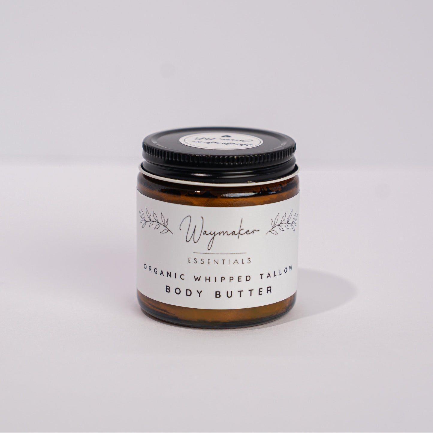 Jar of body butter with a black lid on a white background