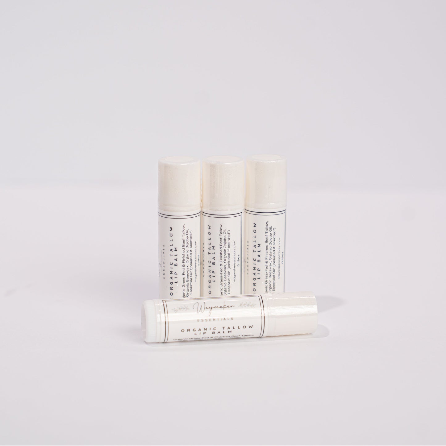 Three white cylindrical products with text on a light gray background - organic lip balm