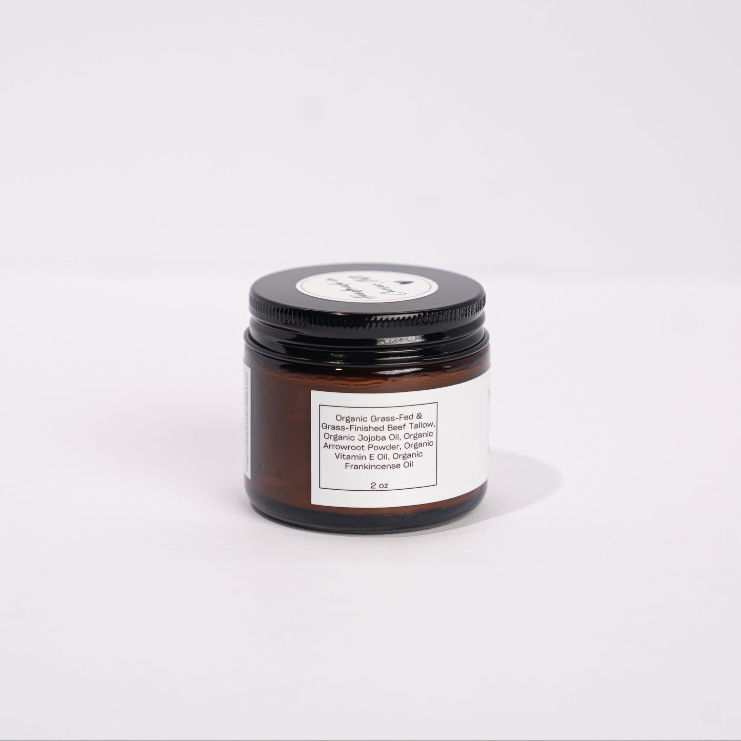 Small jar with a black lid on a white background Organic Beef Tallow Face Balm