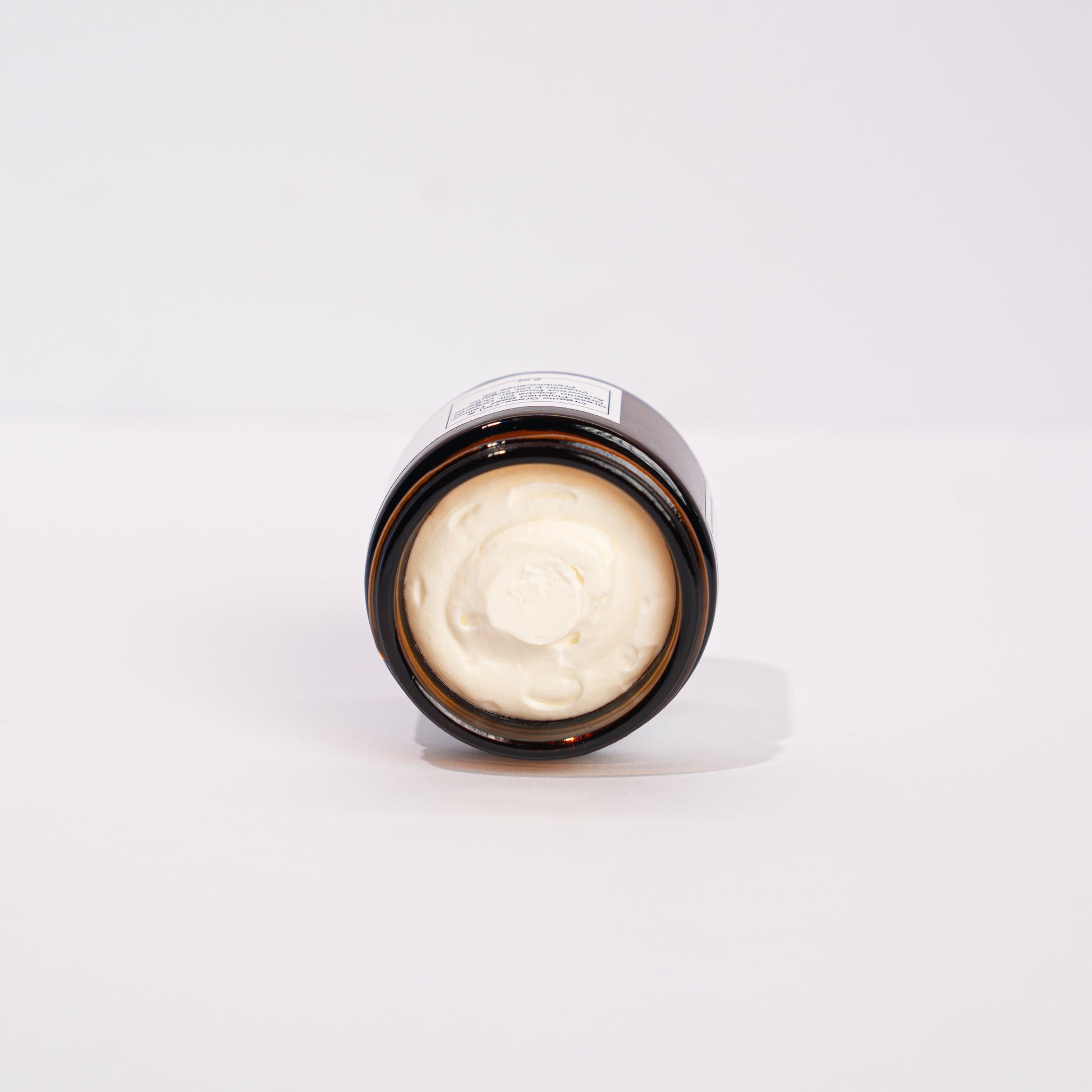 Small round container with a light bulb inside on a white background organic tallow face balm